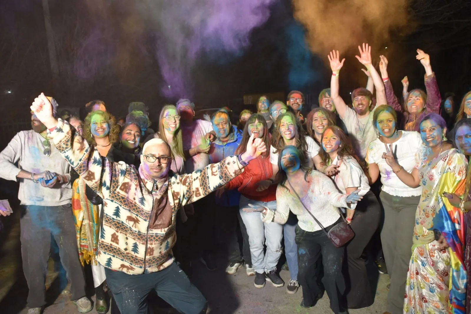 Holi värvidega kaetud rahvas rõõmustab, käed õhus
