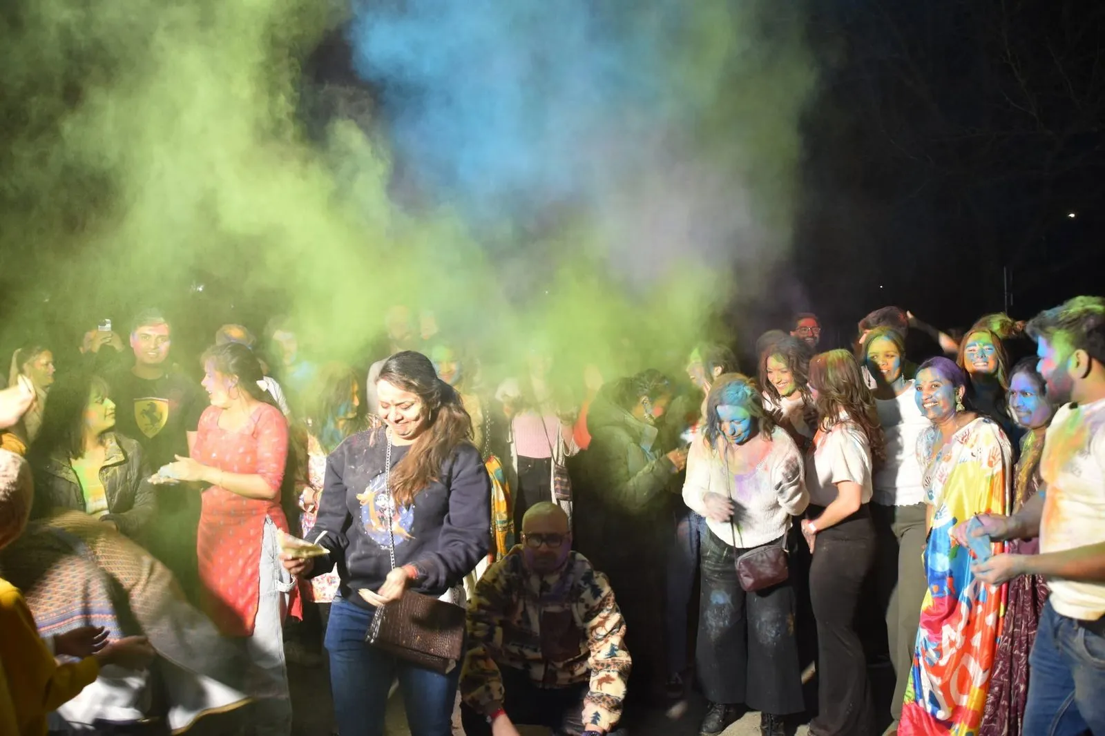 Sinised ja rohelised värvipilved tantsiva rahva kohal